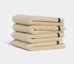 beige face washer towels sitting in a stack on white background