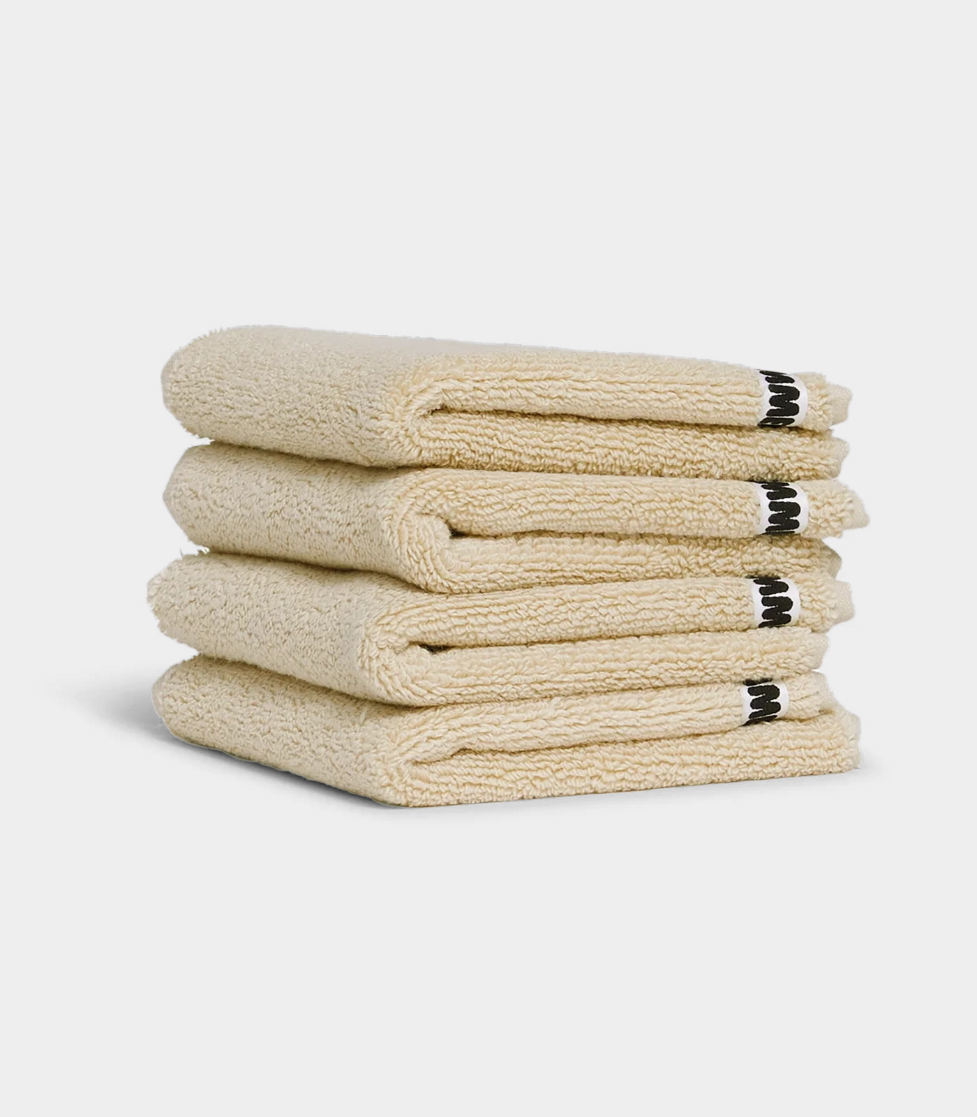 beige face washer towels sitting in a stack on white background