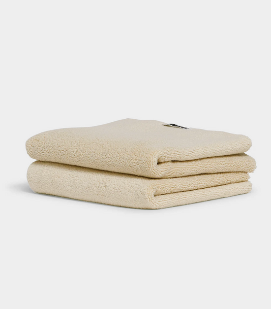 beige towel sitting in stack on white background