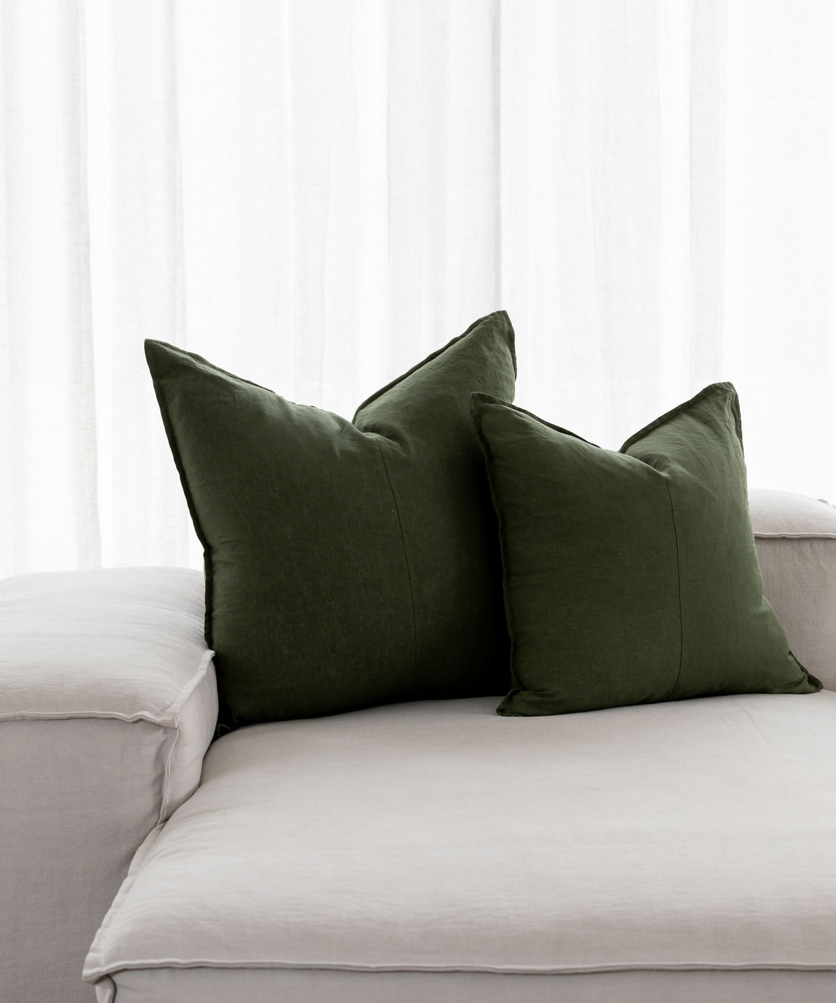 forest green linen cushions sitting on a white couch