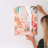 woman hanging up wall art of a Parisian street