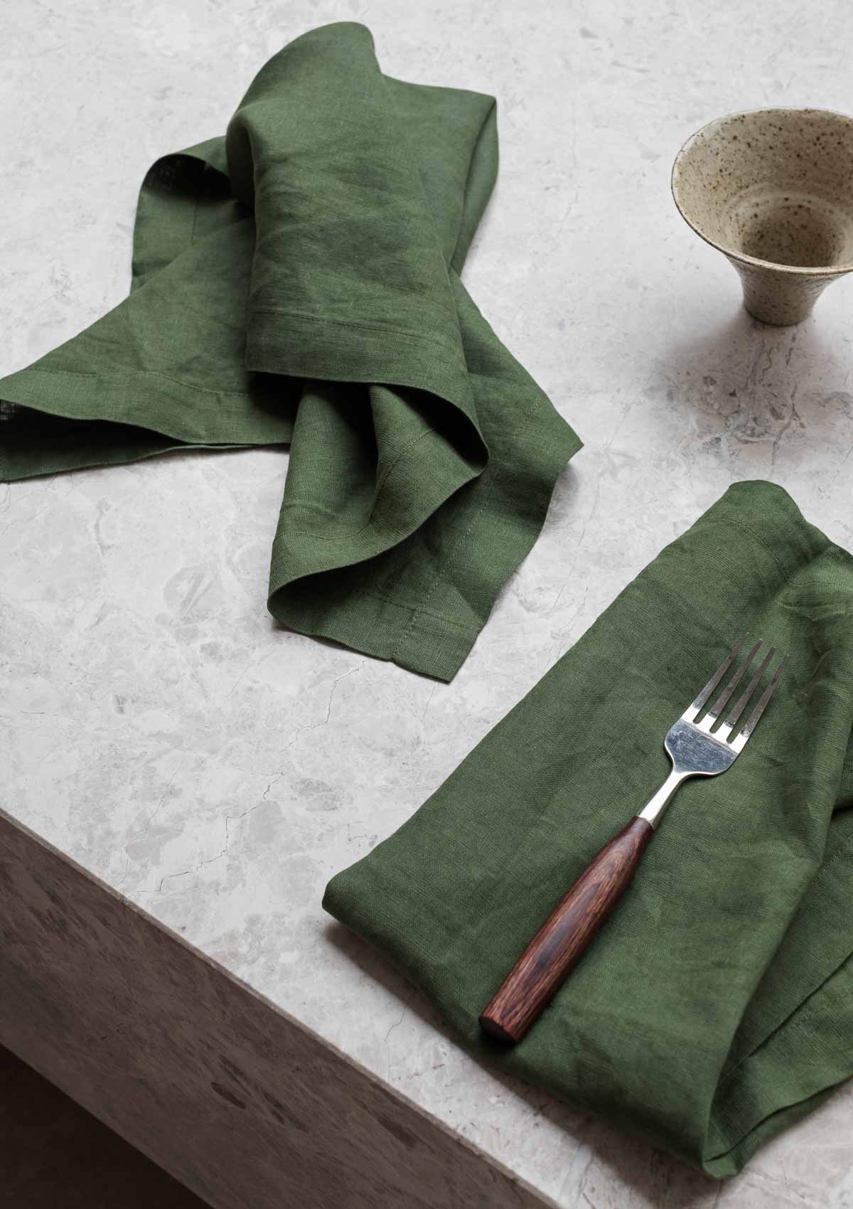 forest green napkin sitting on a marble table 