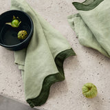 dark green & light green napkins with a wave pattern down the side sitting on a marble table