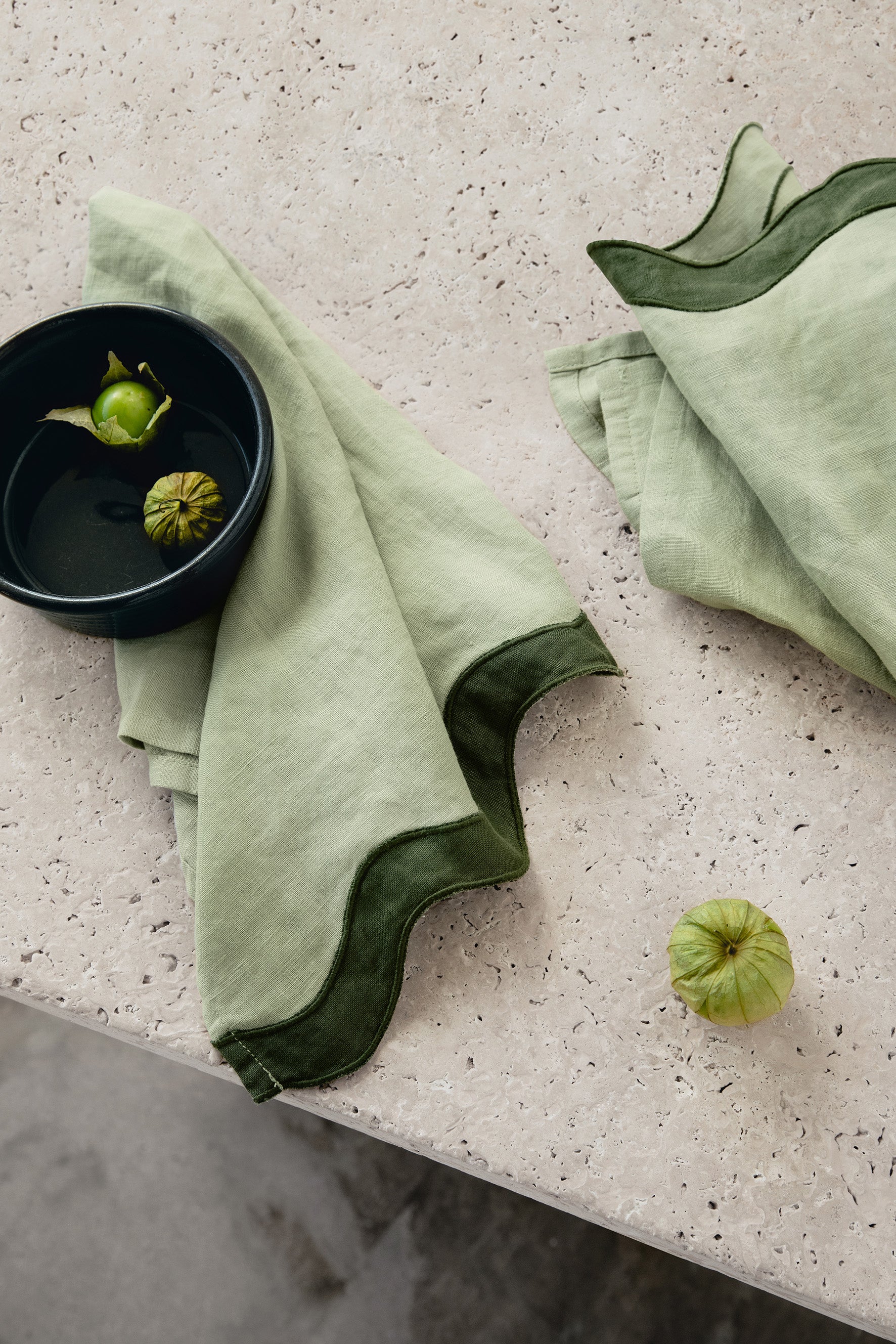 dark green & light green napkins with a wave pattern down the side sitting on a marble table