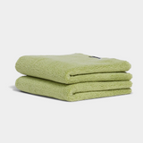 green hand towel sitting in stack on white background