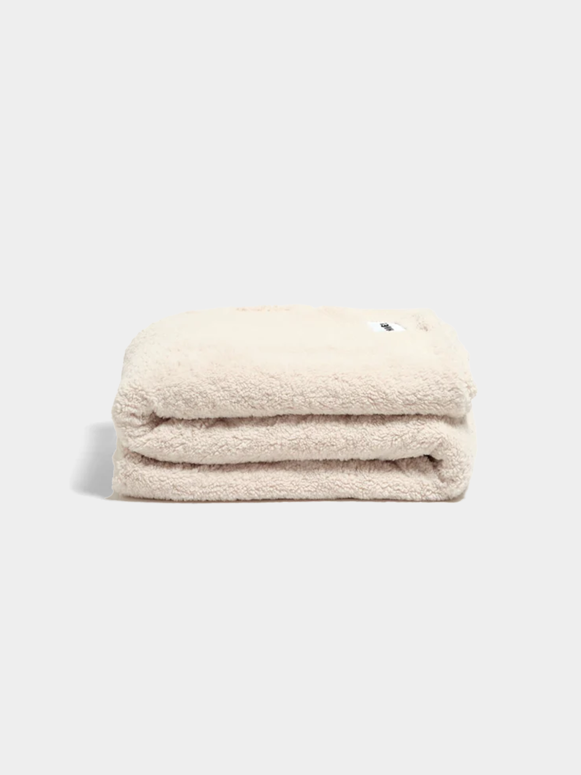 Soft marshmallow-colored faux fur throw blanket folded on white background