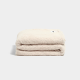 Soft marshmallow-colored faux fur throw blanket folded on white background