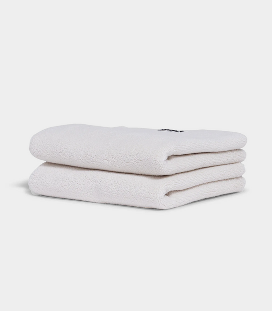 white hand towel sitting in stack on white background