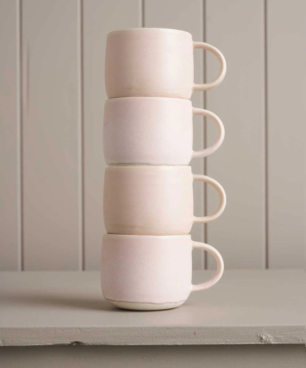 pink mugs sitting on a wooden shelf