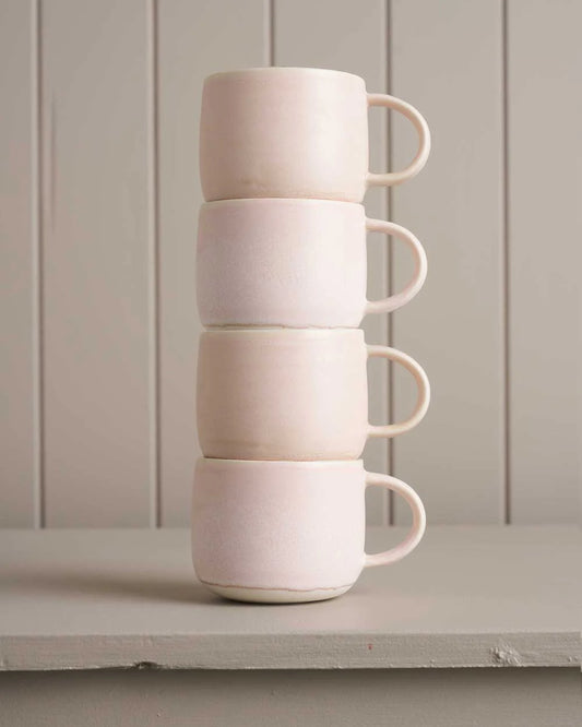 pink mugs sitting on a wooden shelf