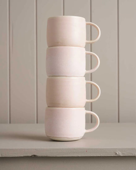 pink mugs sitting on a wooden shelf