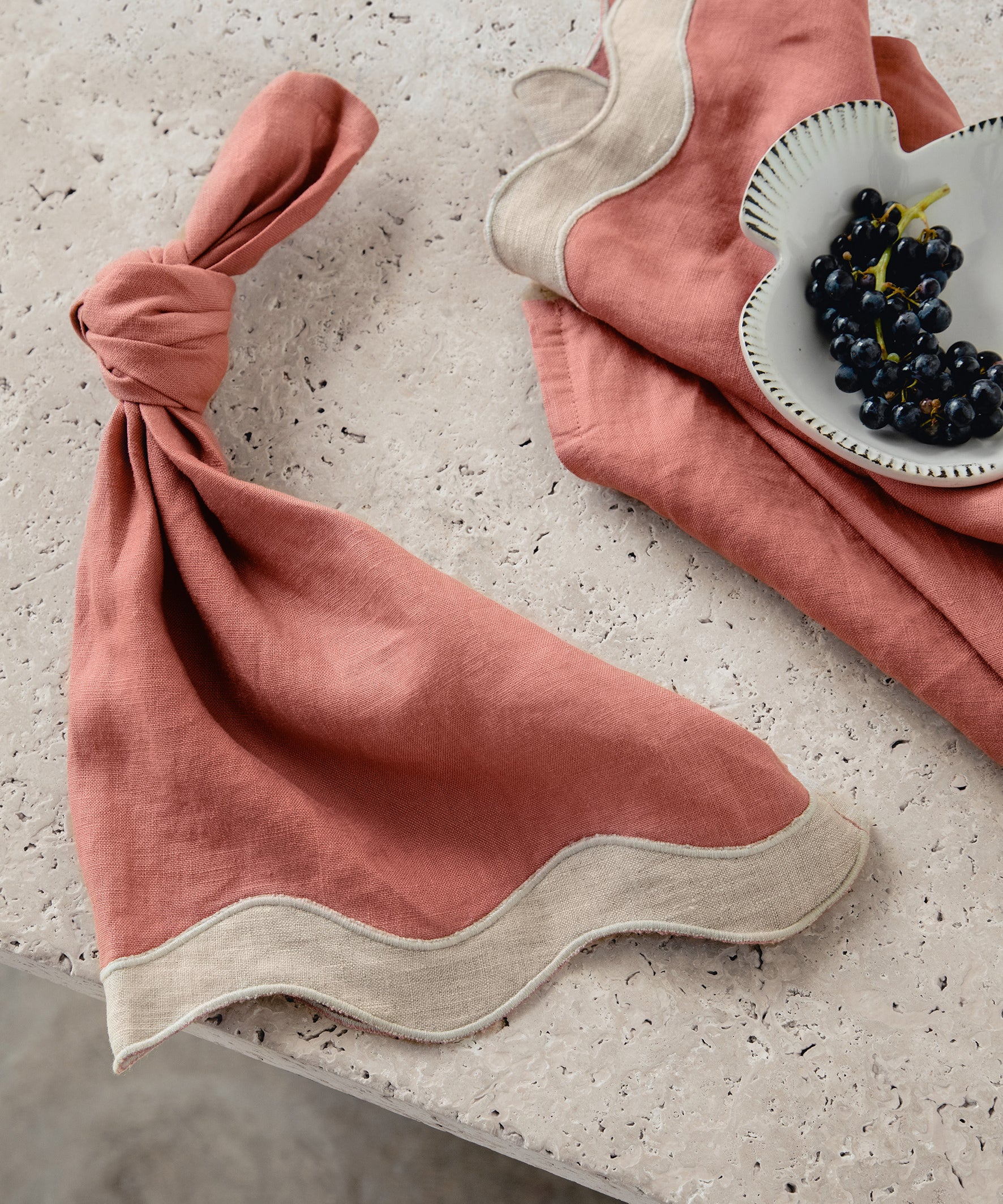  white & pink napkins with a wave pattern down the side sitting on a marble table