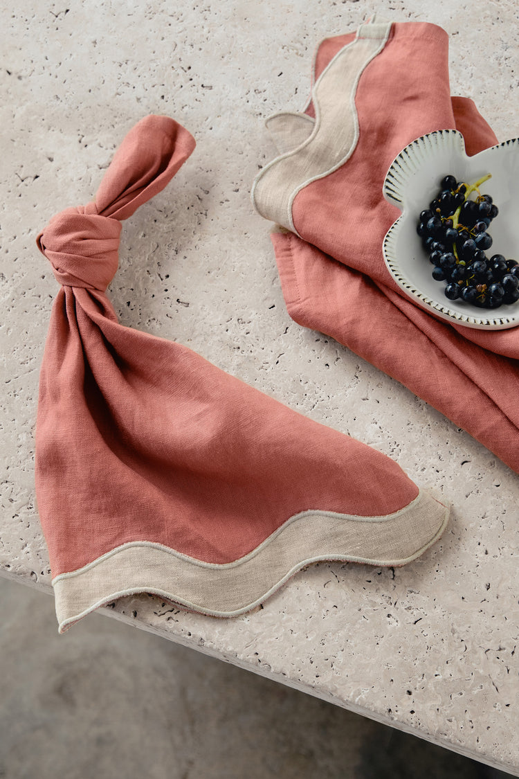  white & pink napkins with a wave pattern down the side sitting on a marble table