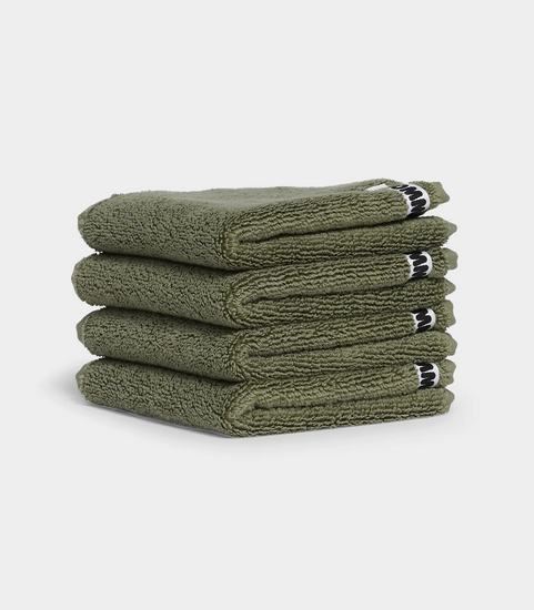 dark green face washer towels in stack on white background