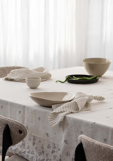 tablescape of a table with napkins, ceramics, tablecloth on it