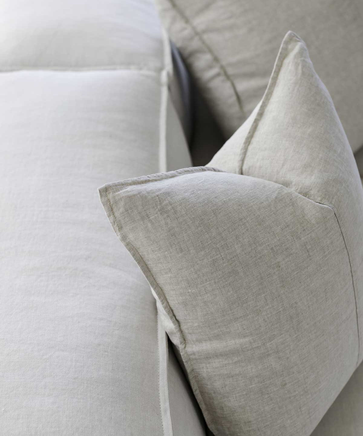 up close image of a beige linen cushion sitting on a couch