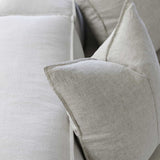 up close image of a beige linen cushion sitting on a couch
