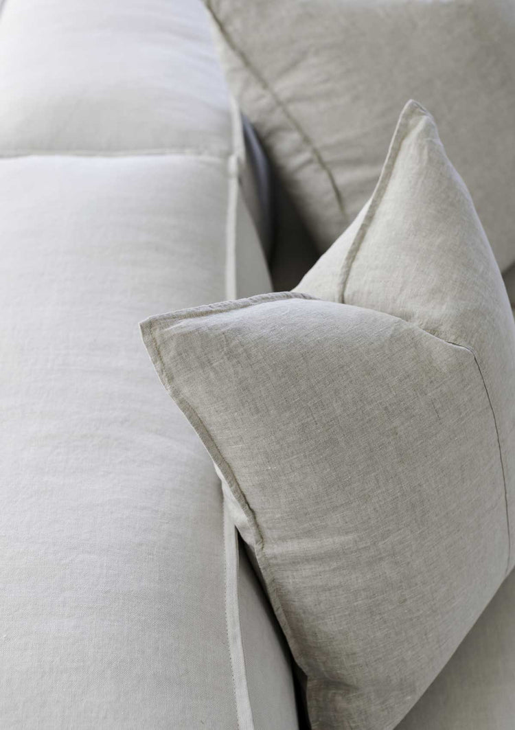 up close image of a beige linen cushion sitting on a couch