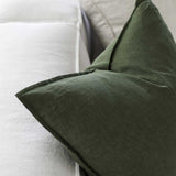 up close image of a forest green linen cushion sitting on a couch 