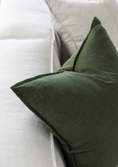 up close image of a forest green linen cushion sitting on a couch 