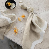 white & beige napkins with a wave pattern down the side sitting on a marble table 
