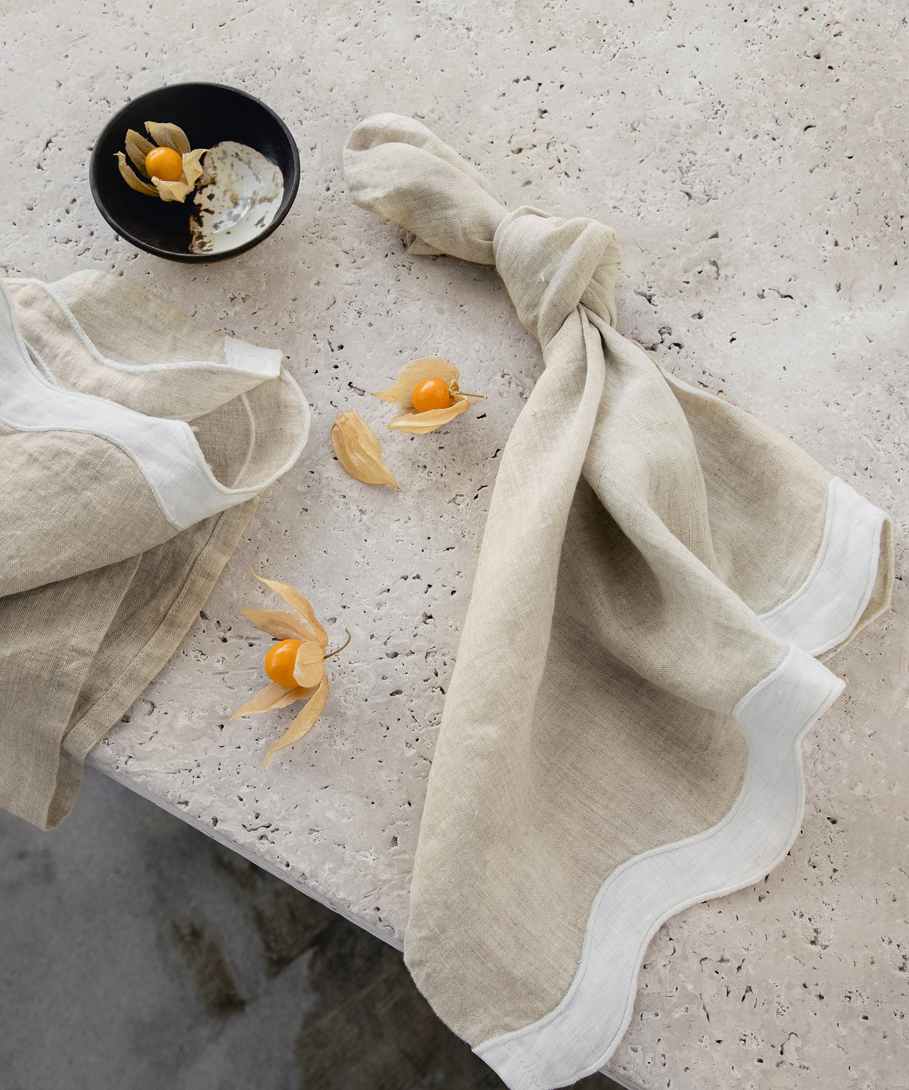 white & beige napkins with a wave pattern down the side sitting on a marble table 