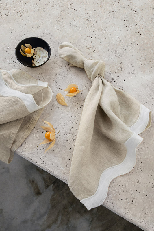 white & beige napkins with a wave pattern down the side sitting on a marble table 