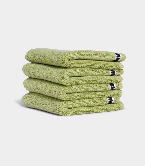 green face washer towels in stack on white background