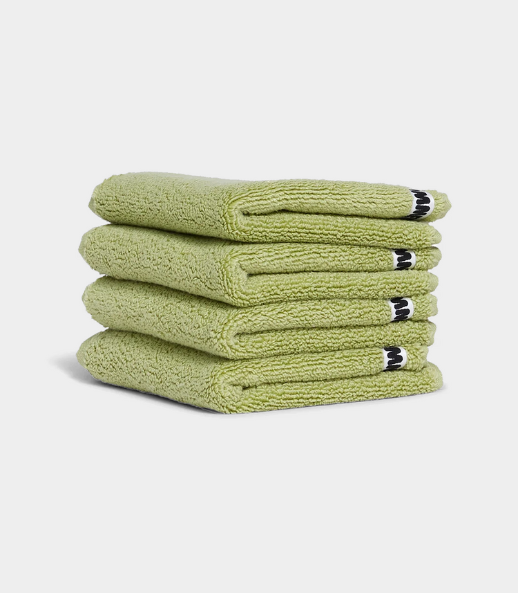 green face washer towels in stack on white background