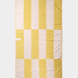 yellow and white beach towel laid out flat